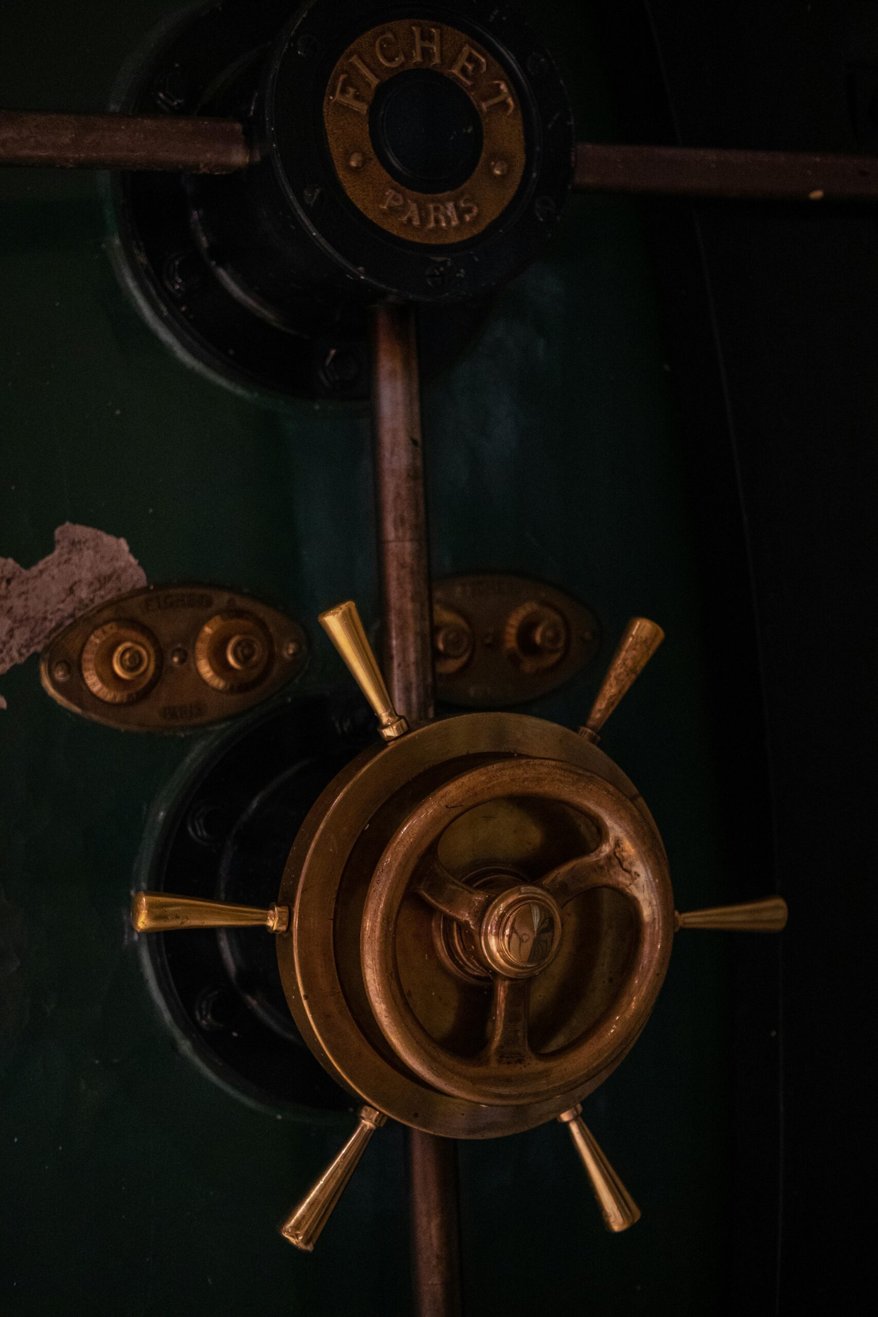 Close-up of a vintage safe door with a brass handle and dark green surface.